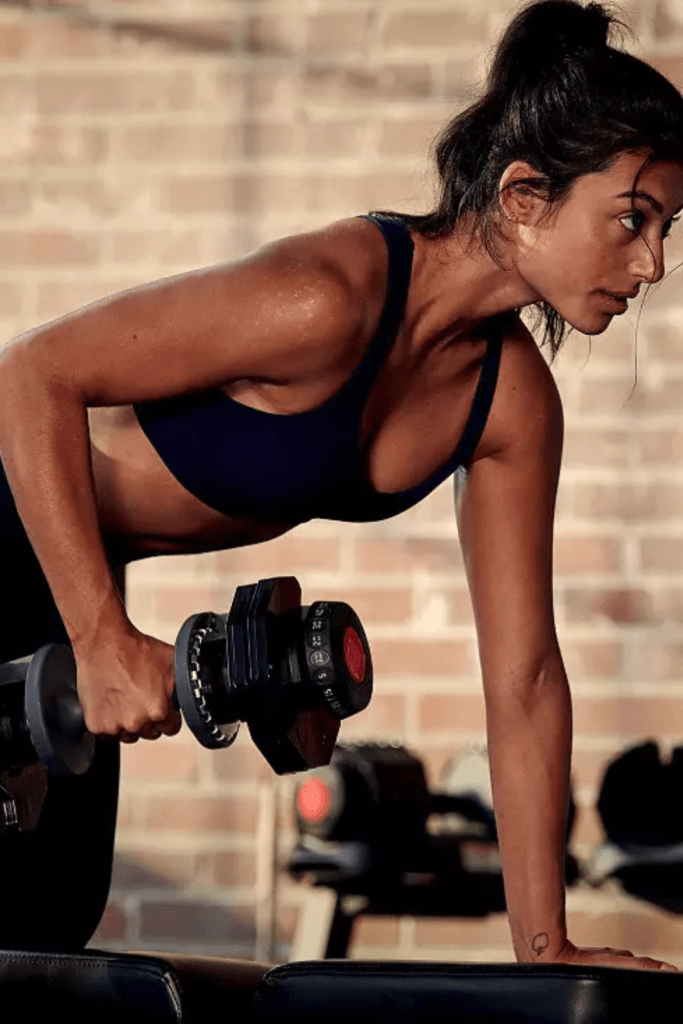 Woman doing a dumbbell workout at home in a bright, comfortable at home gym